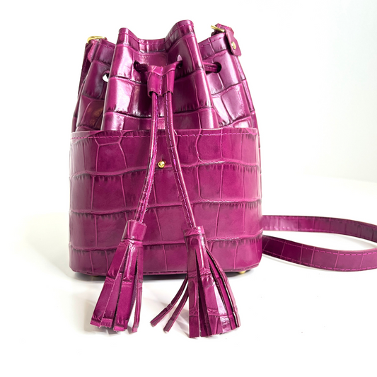 Front view of bucket bag displaying exterior pocket, drawstring and tassels.
