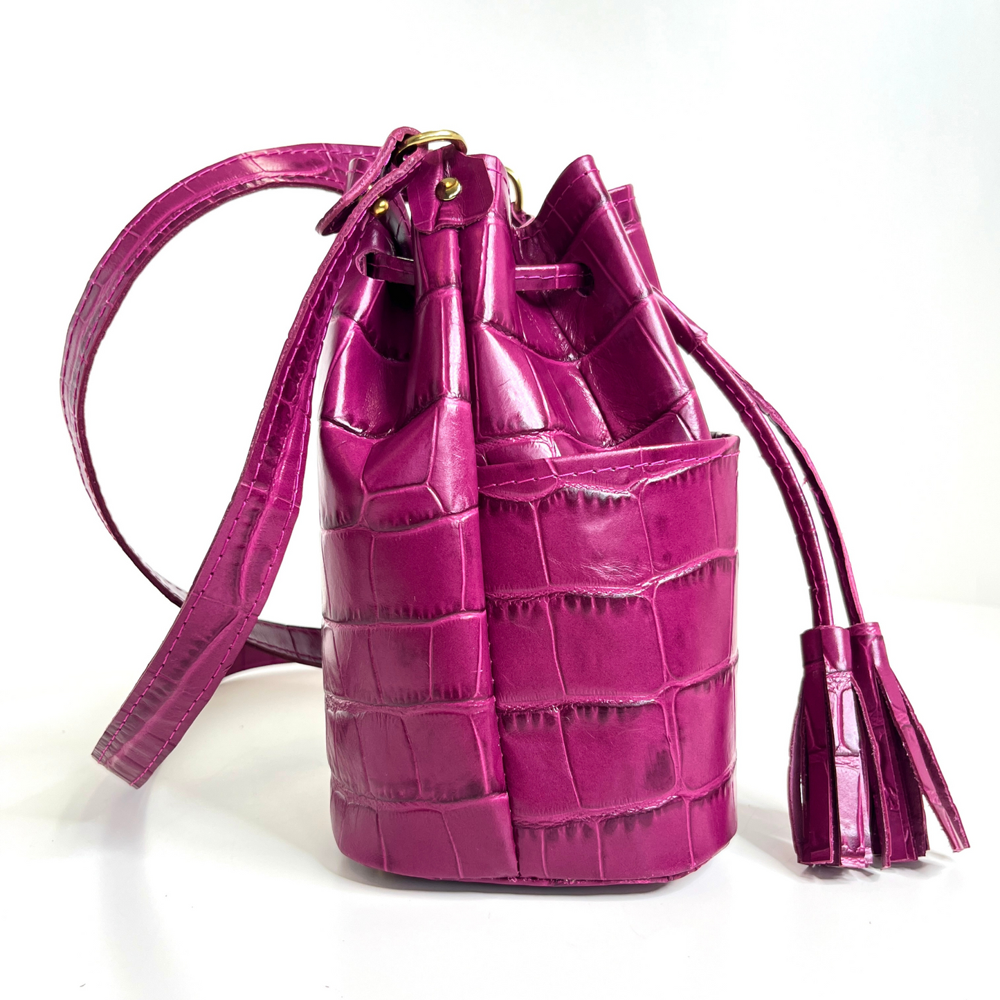 Side view of bucket bag with drawstring taute and strap extended